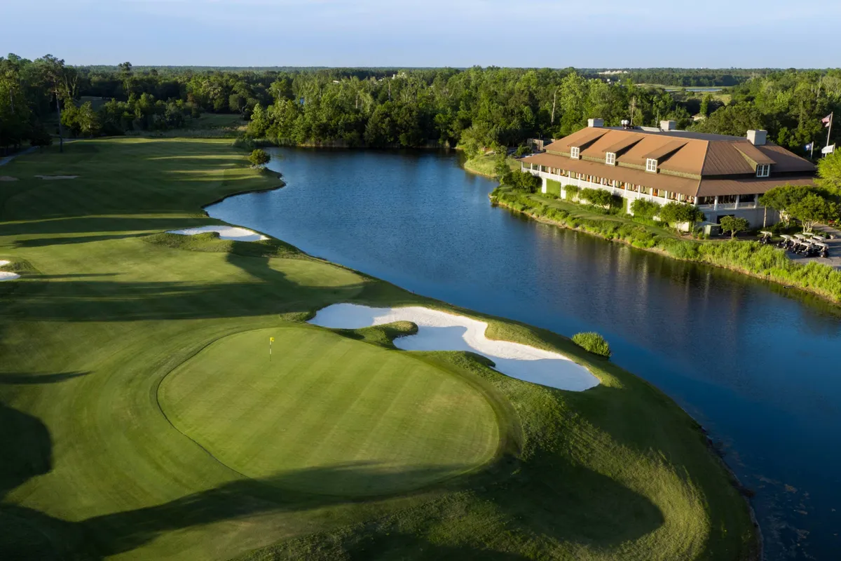 A sweeping exterior view of an expansive golf course, complete with rolling greens, water features that catch the sunset, a stately clubhouse, and well-placed sand traps. The setting is lively yet peaceful, inviting guests to enjoy a round of golf or unwind with friends after a day’s play.