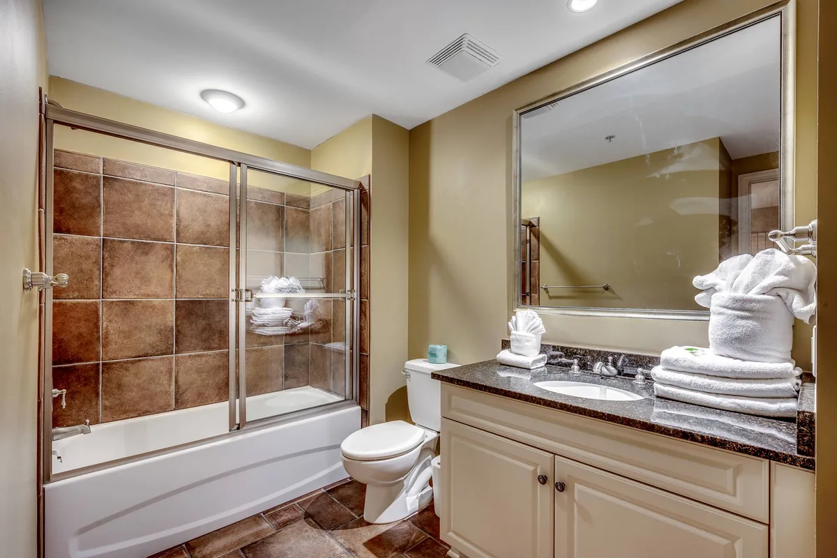 An inviting, spa-like bathroom interior featuring a glass shower enclosure, a vanity with a modern sink, and plush stacked towels. The design exudes serenity and fresh comfort, evoking a high-end, relaxing atmosphere.