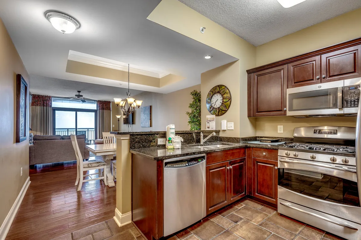 A perspective that showcases a cozy dining area adjacent to a kitchen countertop, with a window view that brings in natural light. The table is set for shared meals, and the overall mood is intimate and inviting, suggesting memorable dinners and morning coffees with an ocean backdrop.