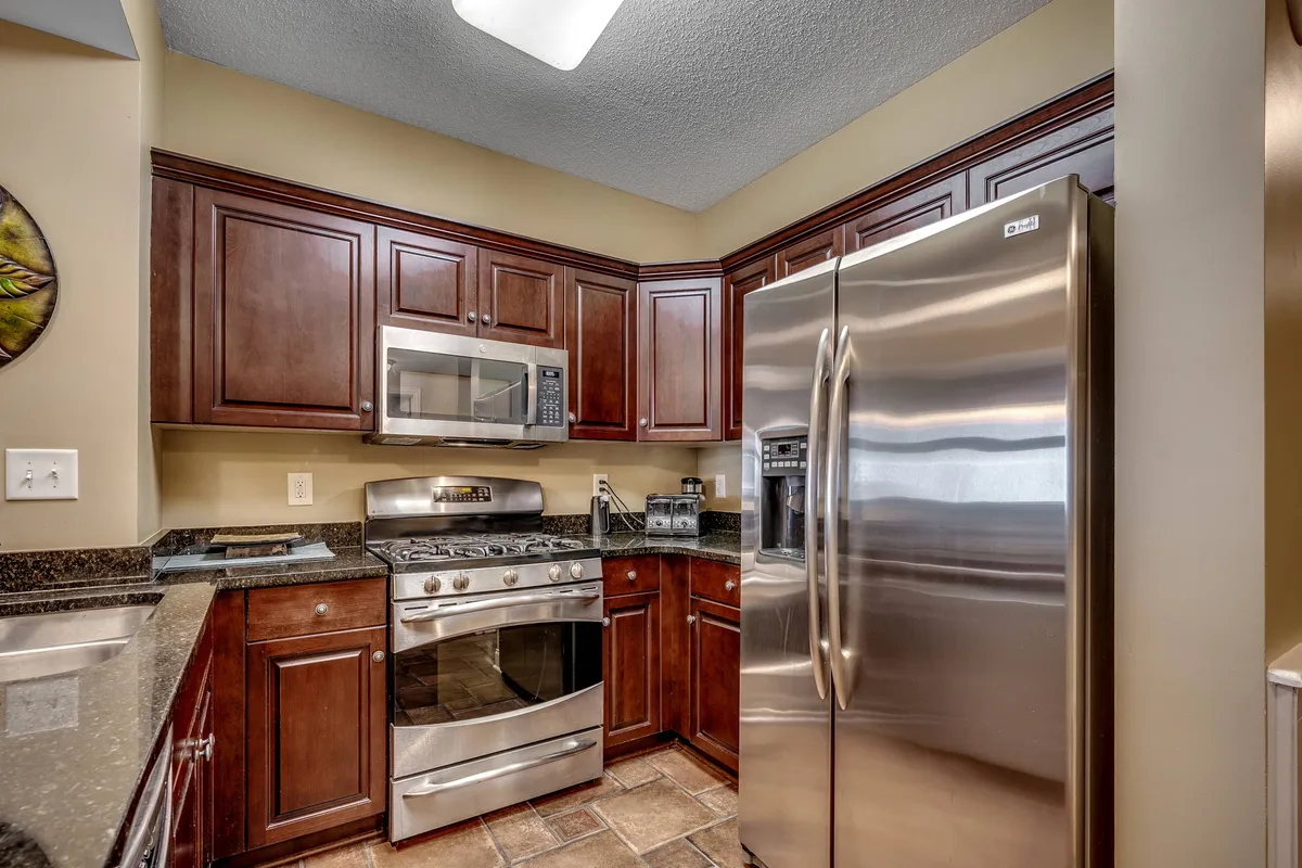 A spacious kitchen featuring modern stainless steel appliances, rich dark wooden cabinetry, and a sleek granite countertop. The space looks inviting and functional, perfect for preparing everything from quick breakfasts to family feasts. The arrangement emphasizes both style and utility, with ample workspace and premium equipment.