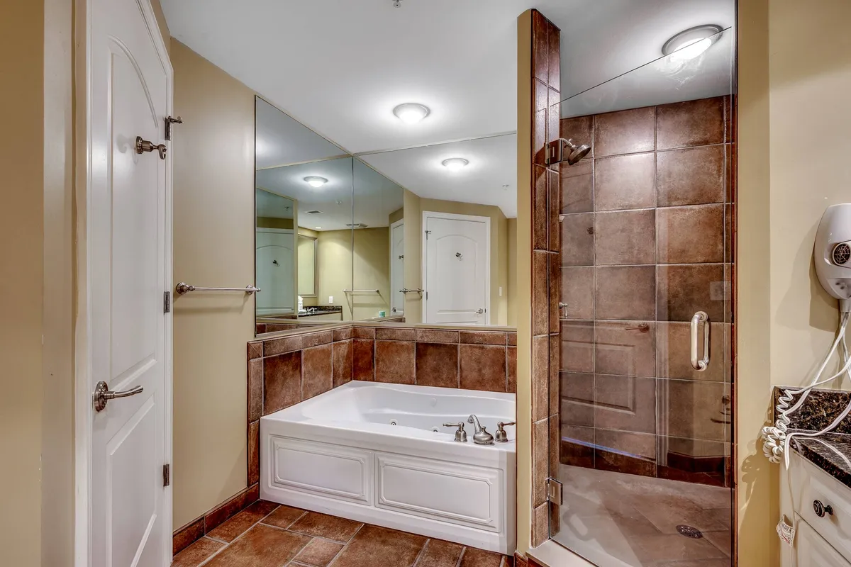 A spa-like bathroom with a deep soaking tub, spacious glass-enclosed shower area, and a mirrored wall that enhances the sense of space and light. The décor is clean, modern, and inviting, perfect for unwinding after a long day.